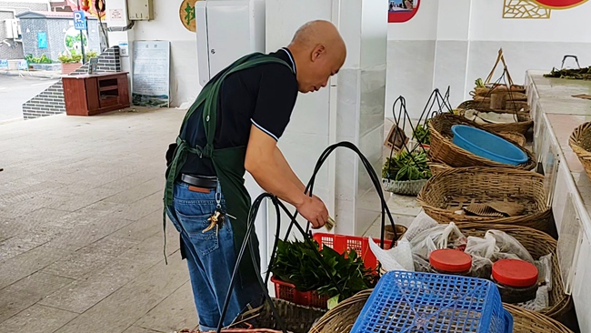 在福建永定不見(jiàn)賣主的自助菜攤，附近居民在挑選蔬菜。永定區(qū)委組織部供圖