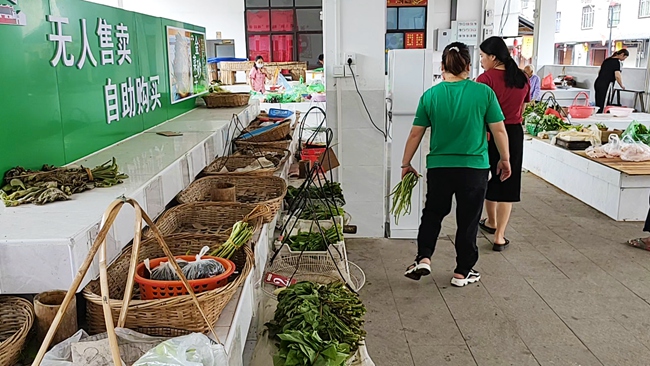 附近居民在自助菜攤買菜。永定區(qū)委組織部供圖