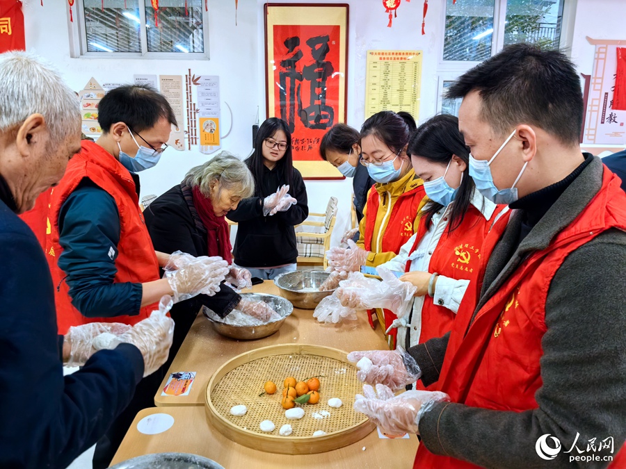 在福州市鼓樓區(qū)屏東社區(qū)長者食堂，老人們正在教年輕人搓芝麻糍。人民網(wǎng) 葉青卿攝